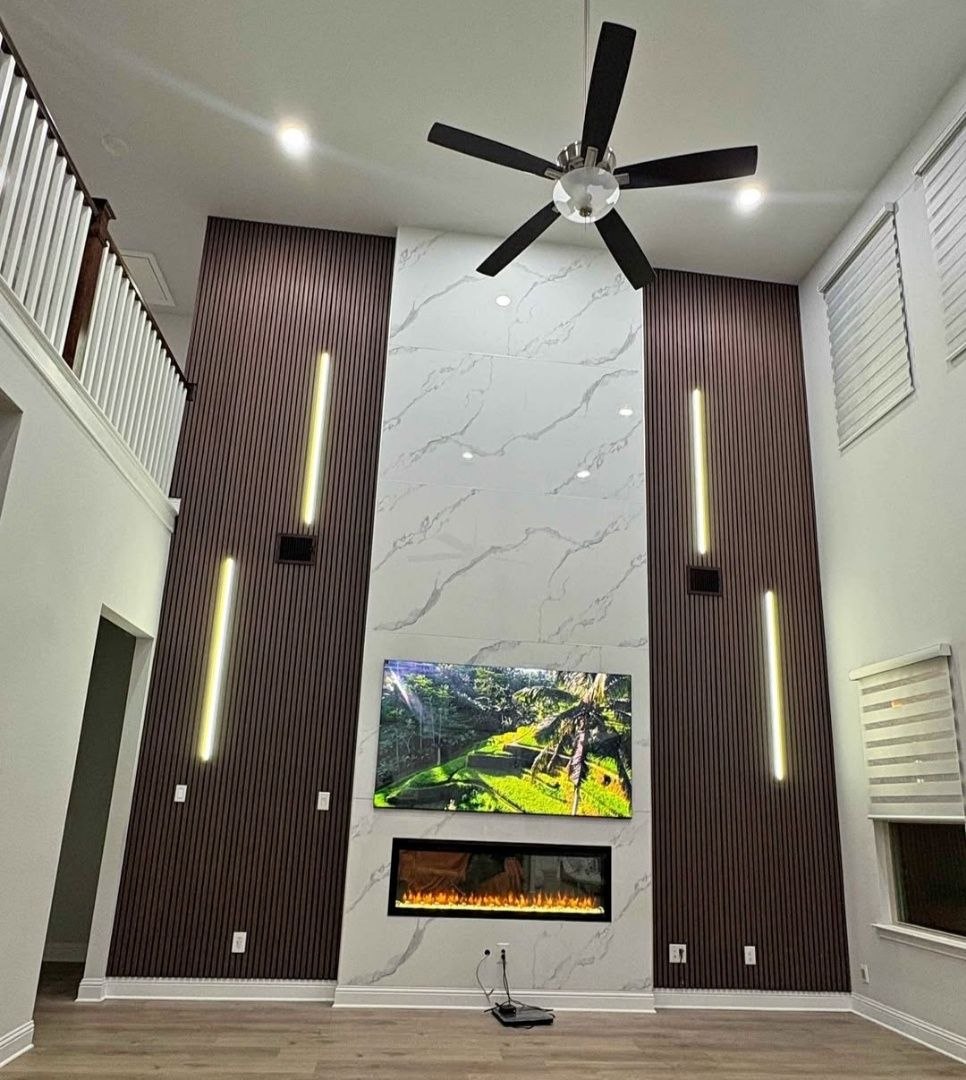Two-story custom TV wall with marble panels and lighting